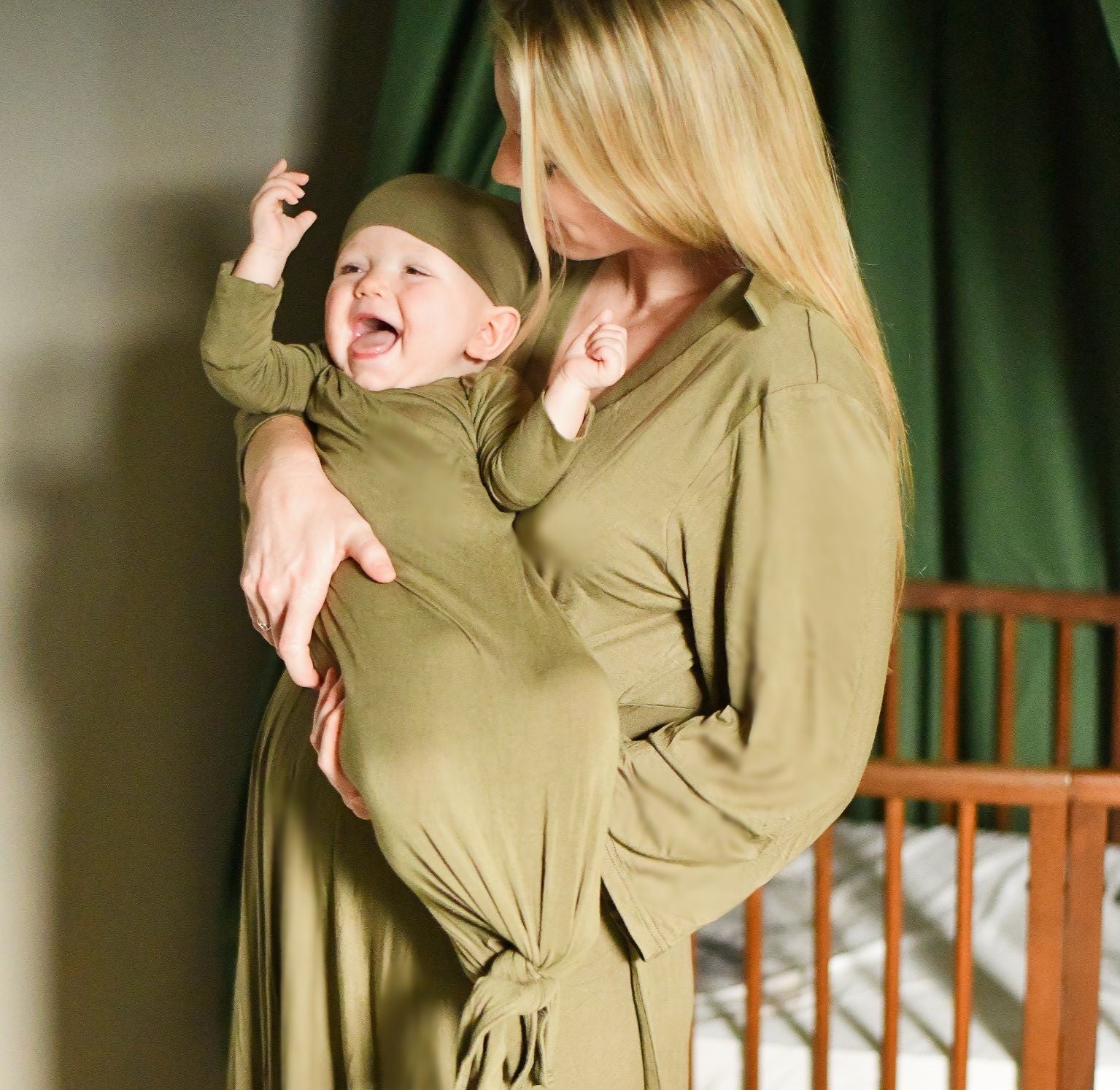 Mom and happy baby wearing matching birth gown and swaddle with hat set